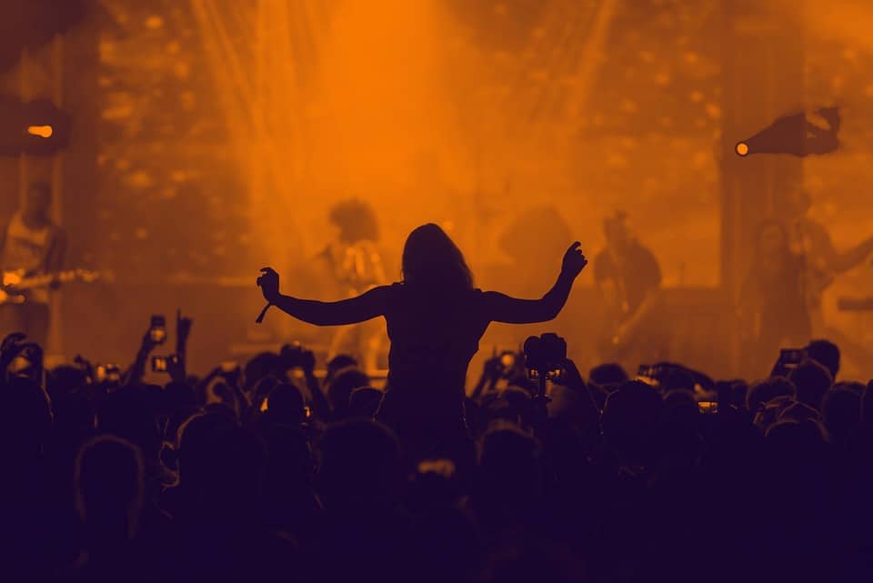 Silhouette of concert crowd under warm stage lighting, brand-neutral, CC0 public domain.