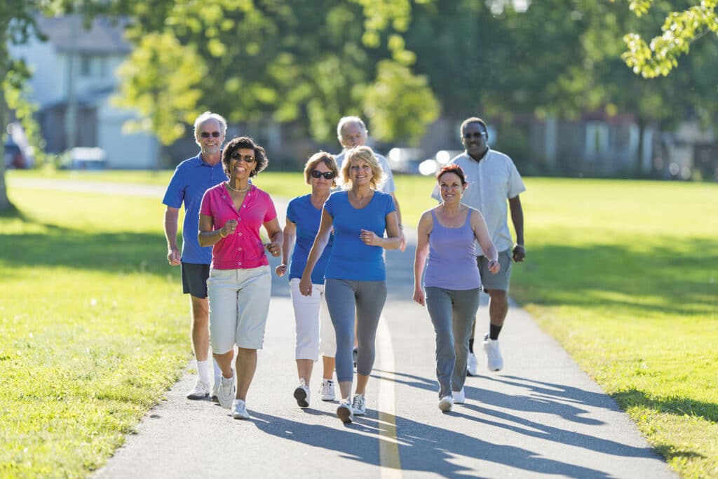 Group of adults walking briskly in the park to stay active and maintain a healthier lifestyle